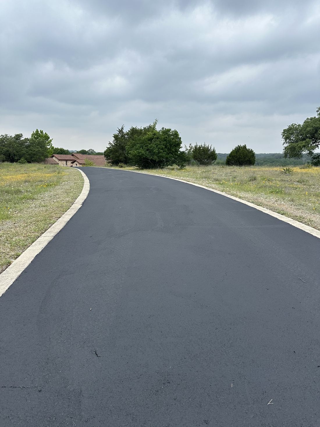 Curved freshly paved driveway winding through Hill Country