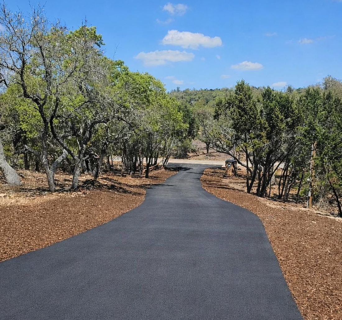Tree-lined asphalt driveway paved by Brooks Asphalt for a Hill Country home
